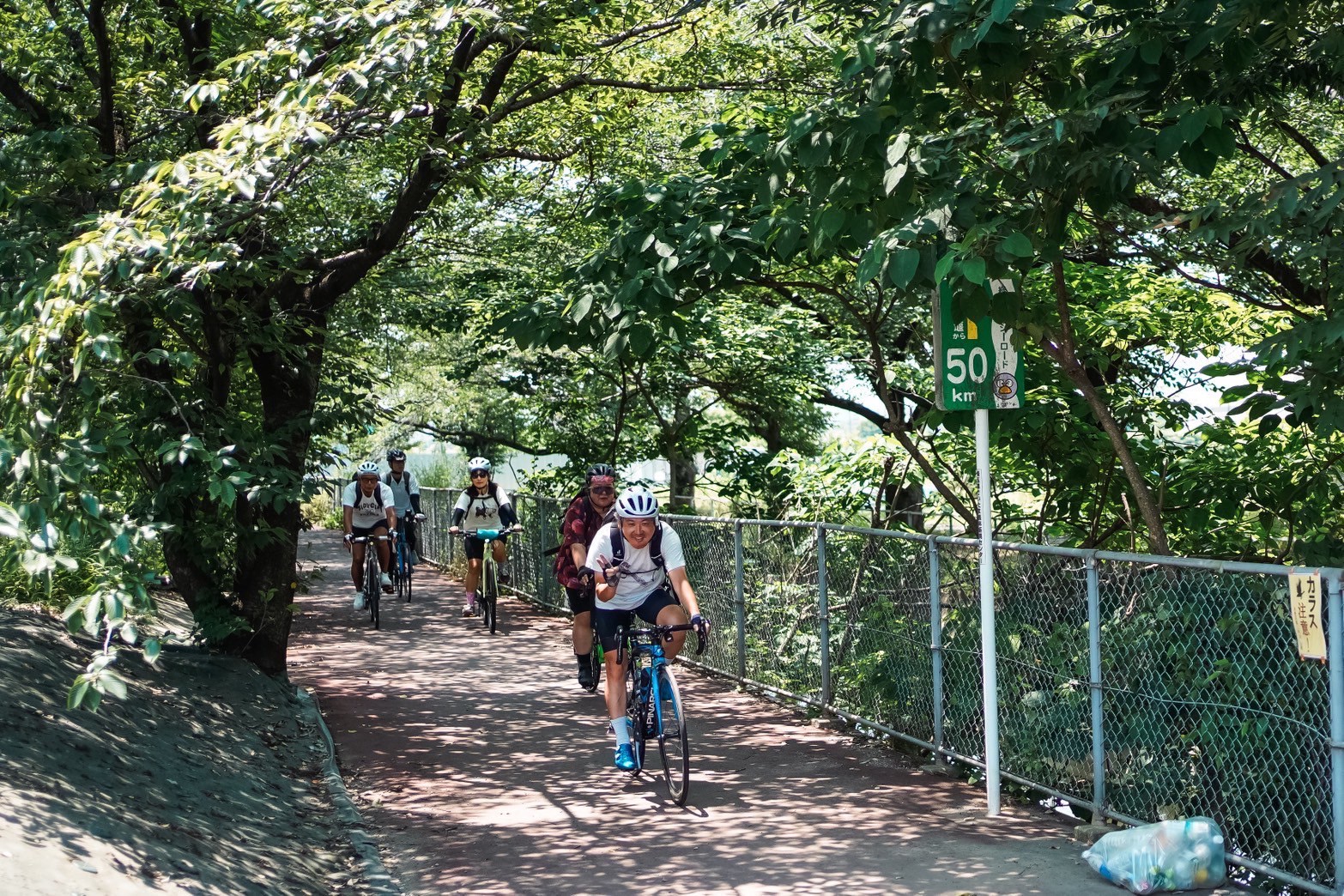 緑のサイクリングロードを走る参加者の列
